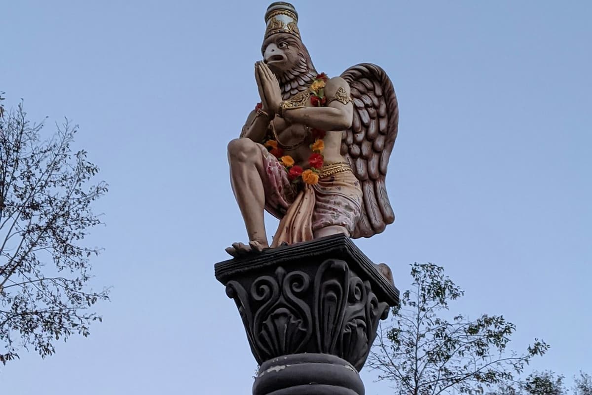 A kneeling Garuda statue on a carved pillar at Budhanilkantha temple, the start of the Bishnudwar hike near Kathmandu.