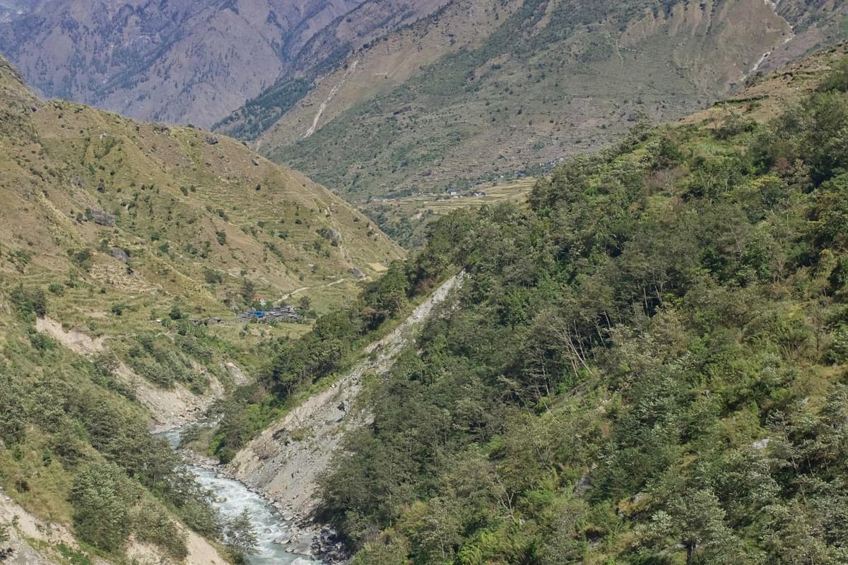 The trail cut into the wall of a deep forested river canyon on the Manaslu Circuit trek from Kathmandu