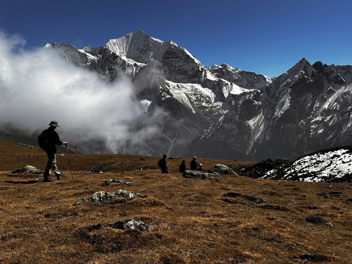 Trekkers crossing a high ridge below snow peaks on the Langtang Valley trek