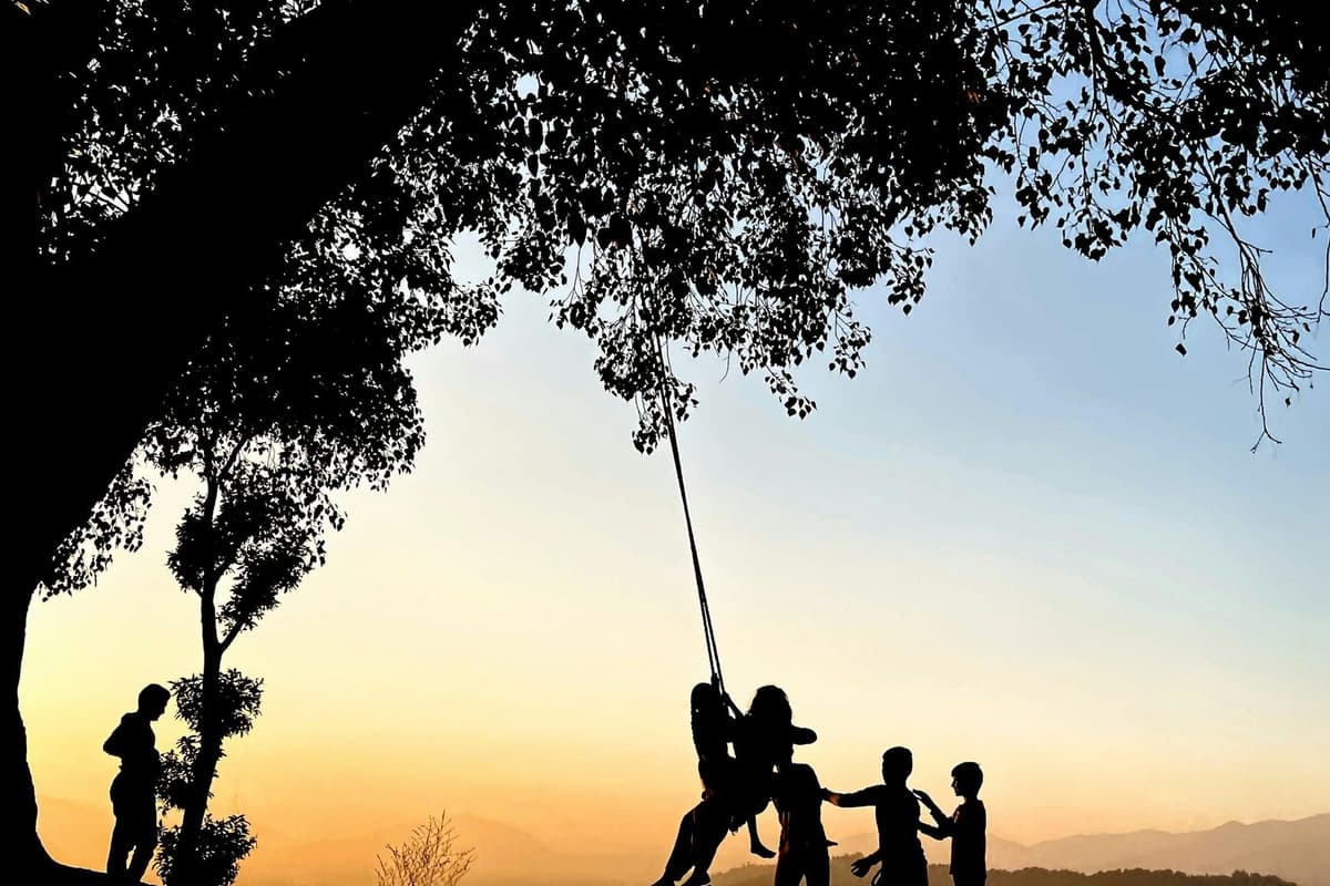 Silhouettes on a hilltop swing at sunset in Nagarkot, a moment from the Changu Narayan to Nagarkot hike.