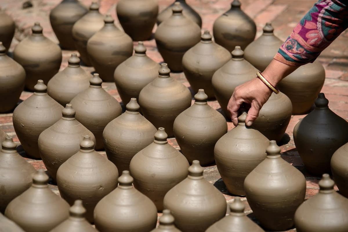 A potter arranging freshly thrown clay pots in Bhaktapur, part of the pottery session on the Nepali cooking class.