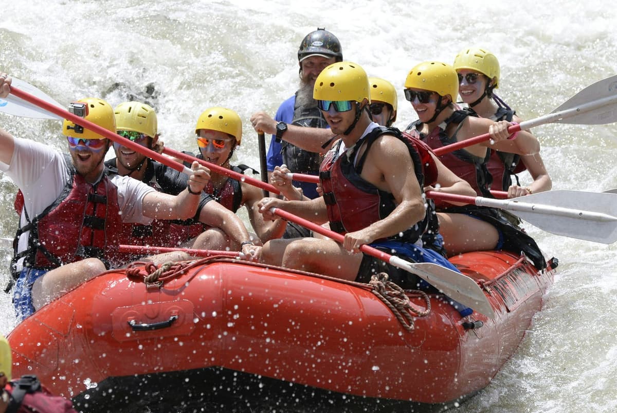 Rafters in helmets and life jackets paddling together on a Trishuli River rafting trip