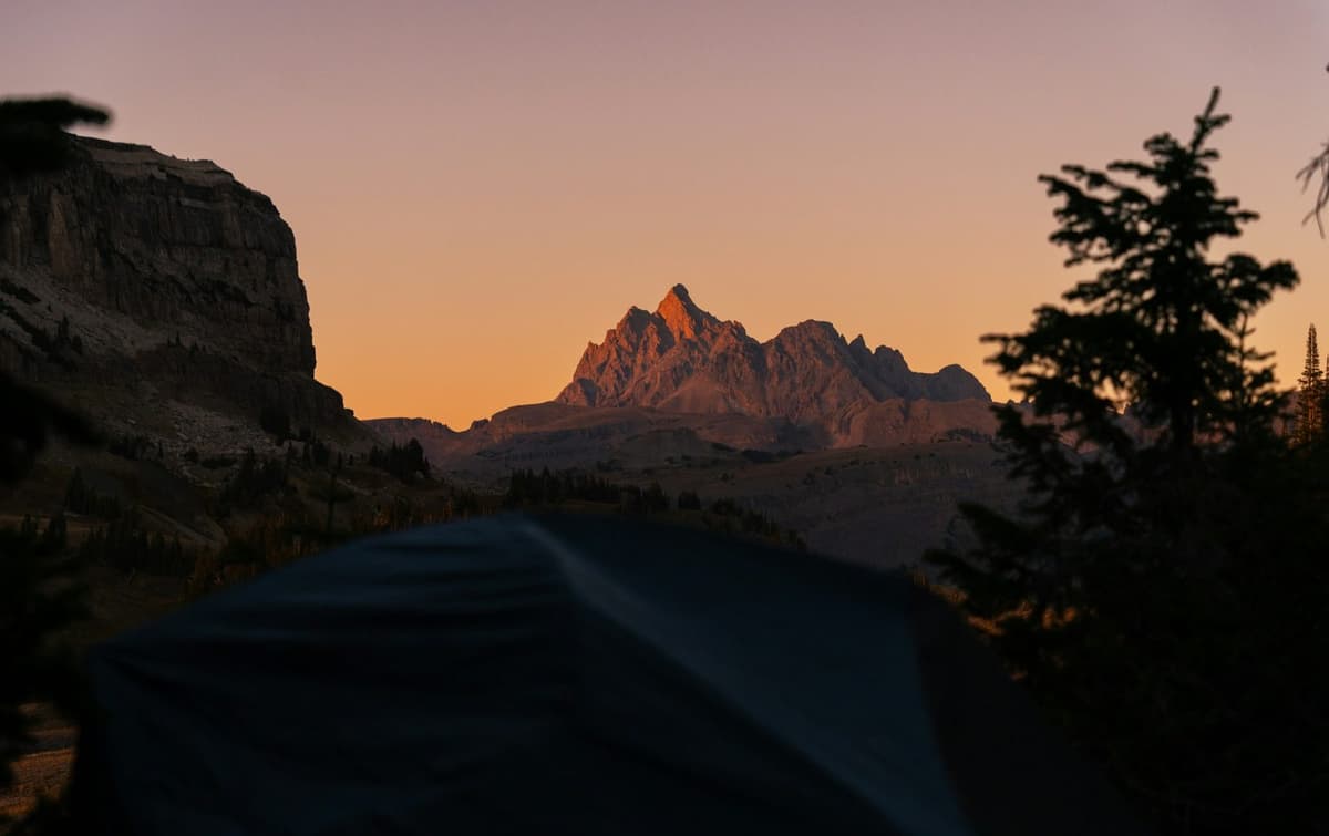 A tent silhouetted against mountain peaks at first light on the Kakani camping trip