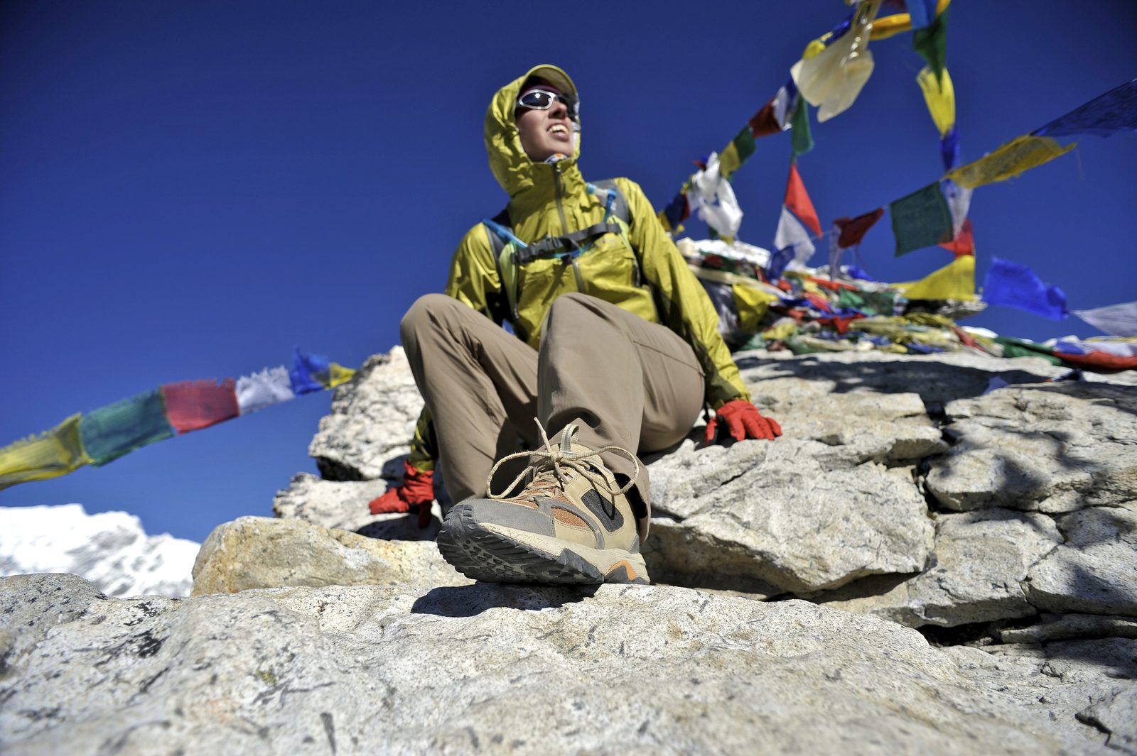 Trekker resting among prayer flags at a high viewpoint on the Everest Base Camp trek
