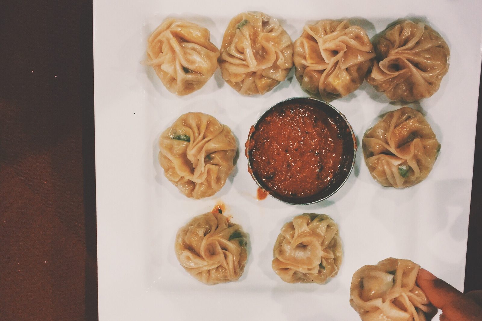 Hand-pleated momo around a bowl of chilli sauce, the folding technique taught on the momo making class.