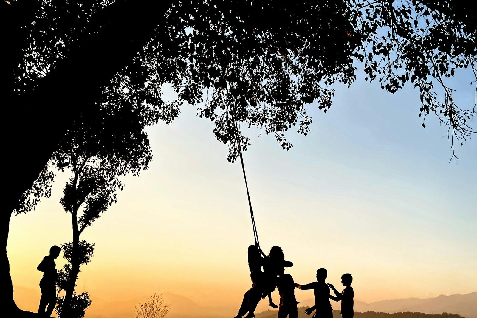 Silhouettes on a hilltop swing at sunset in Nagarkot, a moment from the Changu Narayan to Nagarkot hike.