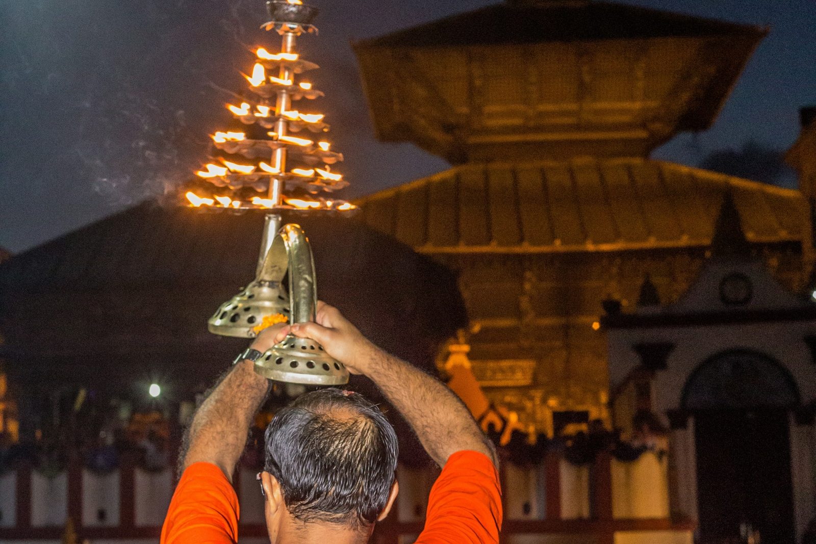 A priest raising the many-flamed lamp during the evening Pashupatinath aarti, the heart of this Boudhanath and Pashupatinath aarti tour.