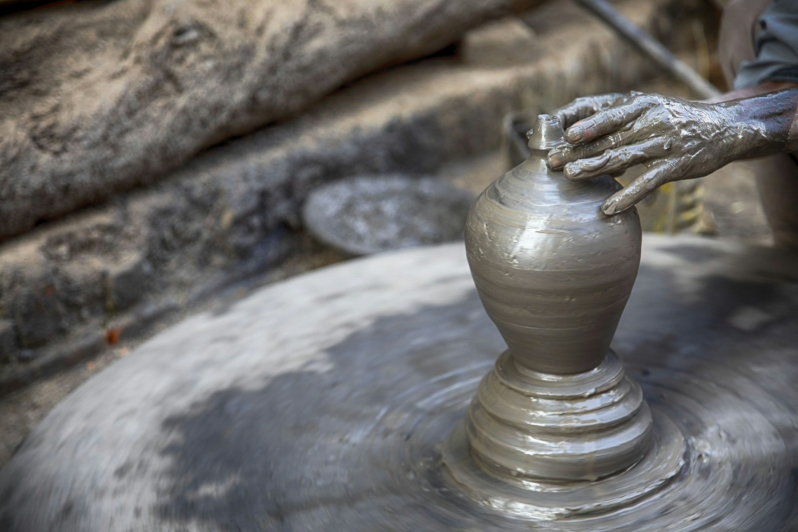Hands shaping clay on a potter's wheel at Pottery Square in Bhaktapur, the craft you try after the Nepali cooking class.