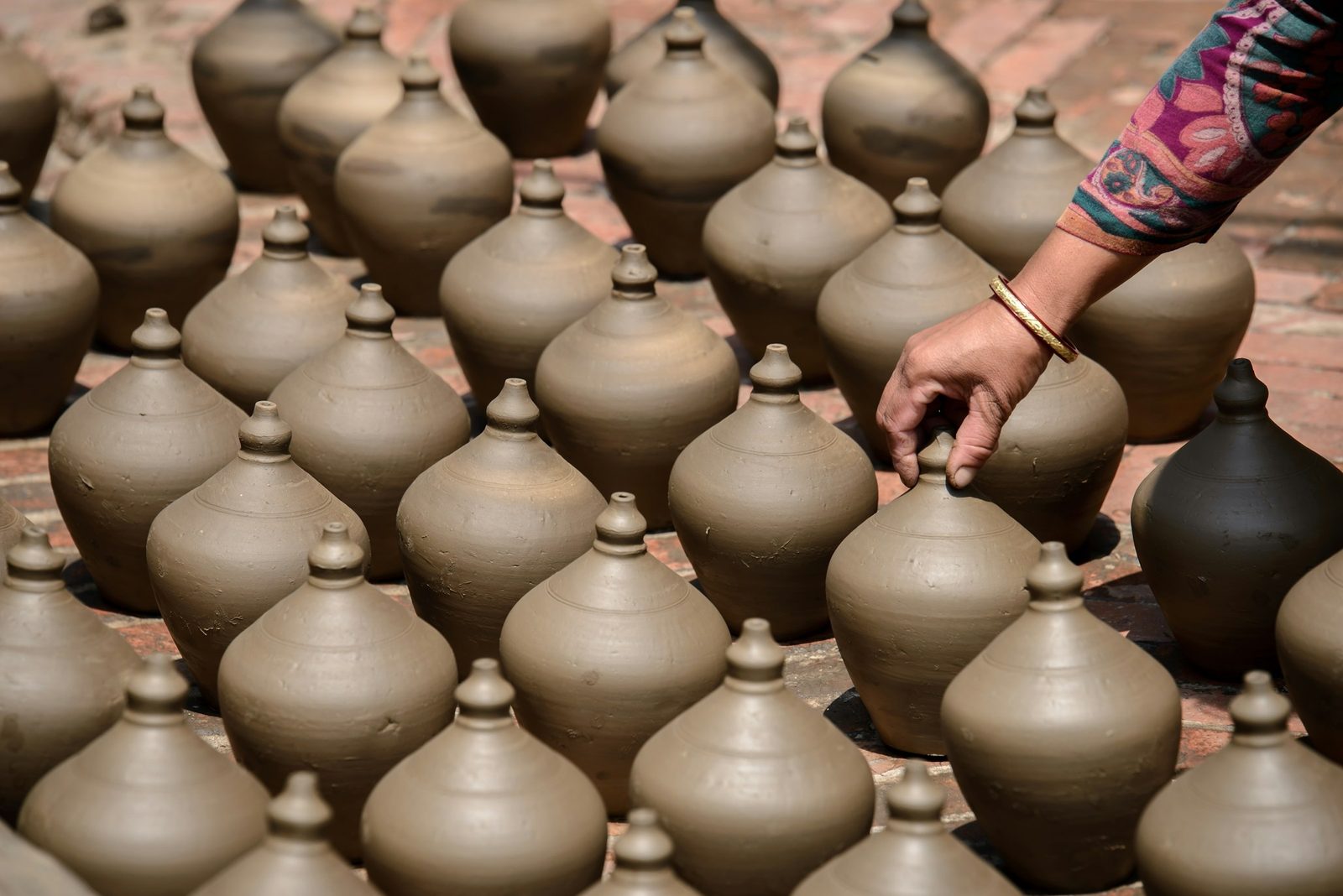 A potter arranging freshly thrown clay pots in Bhaktapur, part of the pottery session on the Nepali cooking class.