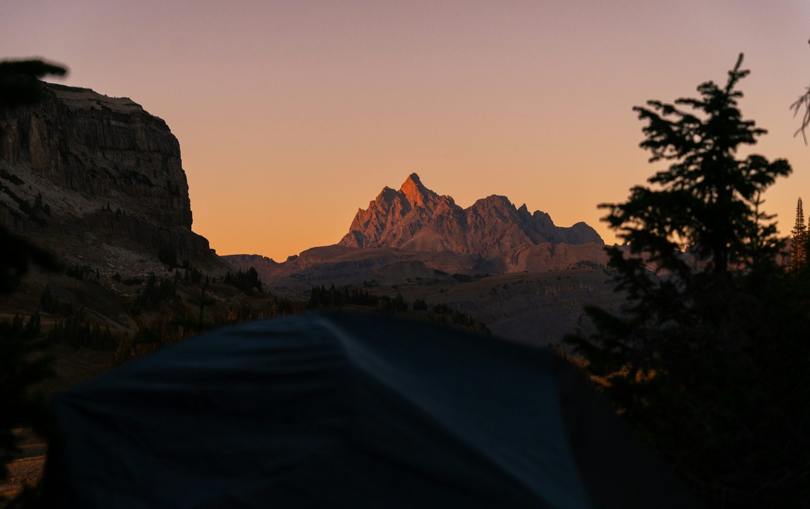 A tent silhouetted against mountain peaks at first light on the Kakani camping trip
